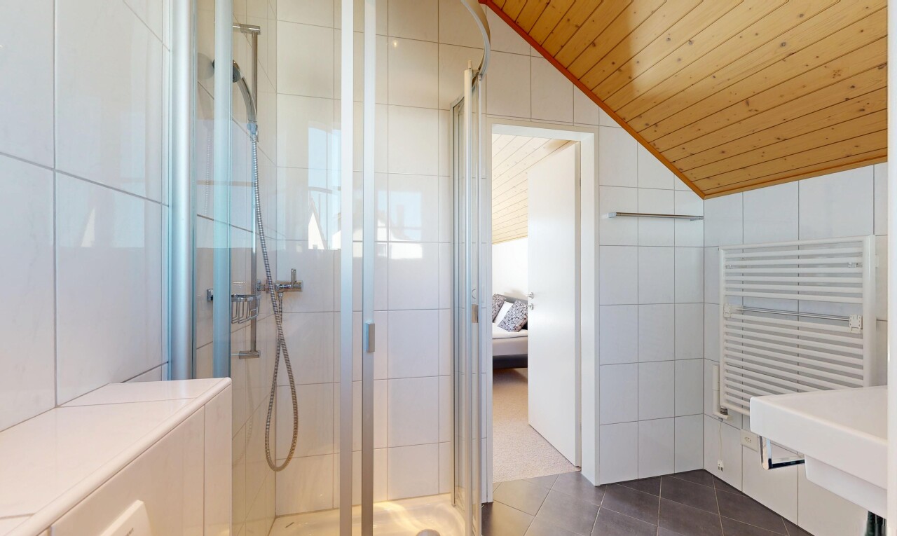 full bathroom with radiator heating unit, tile walls, a shower stall, dark tile patterned flooring, and ensuite bath