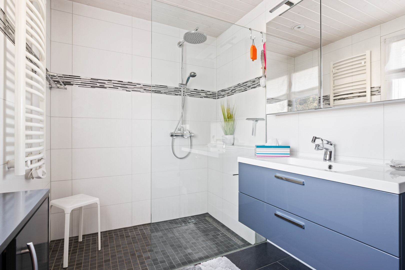 full bath featuring a towel warmer, vanity, radiator, walk in shower, and tile walls