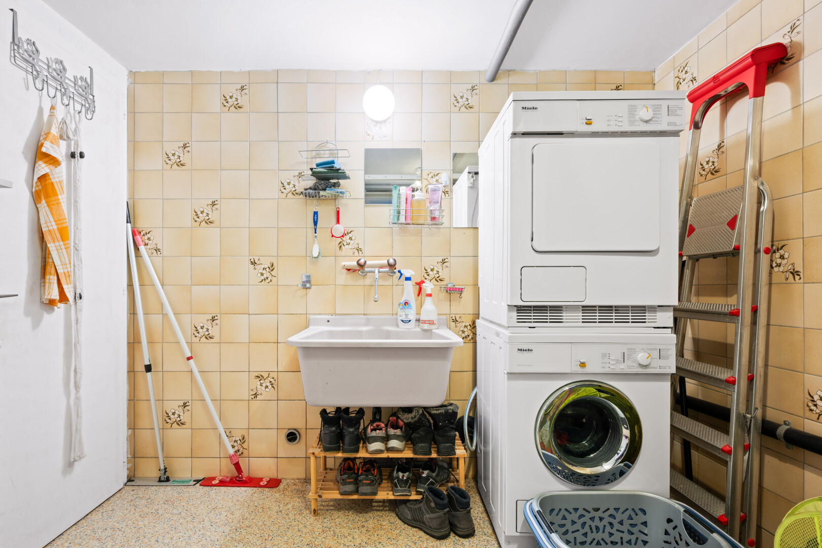 laundry area with stacked washer and clothes dryer and tile walls