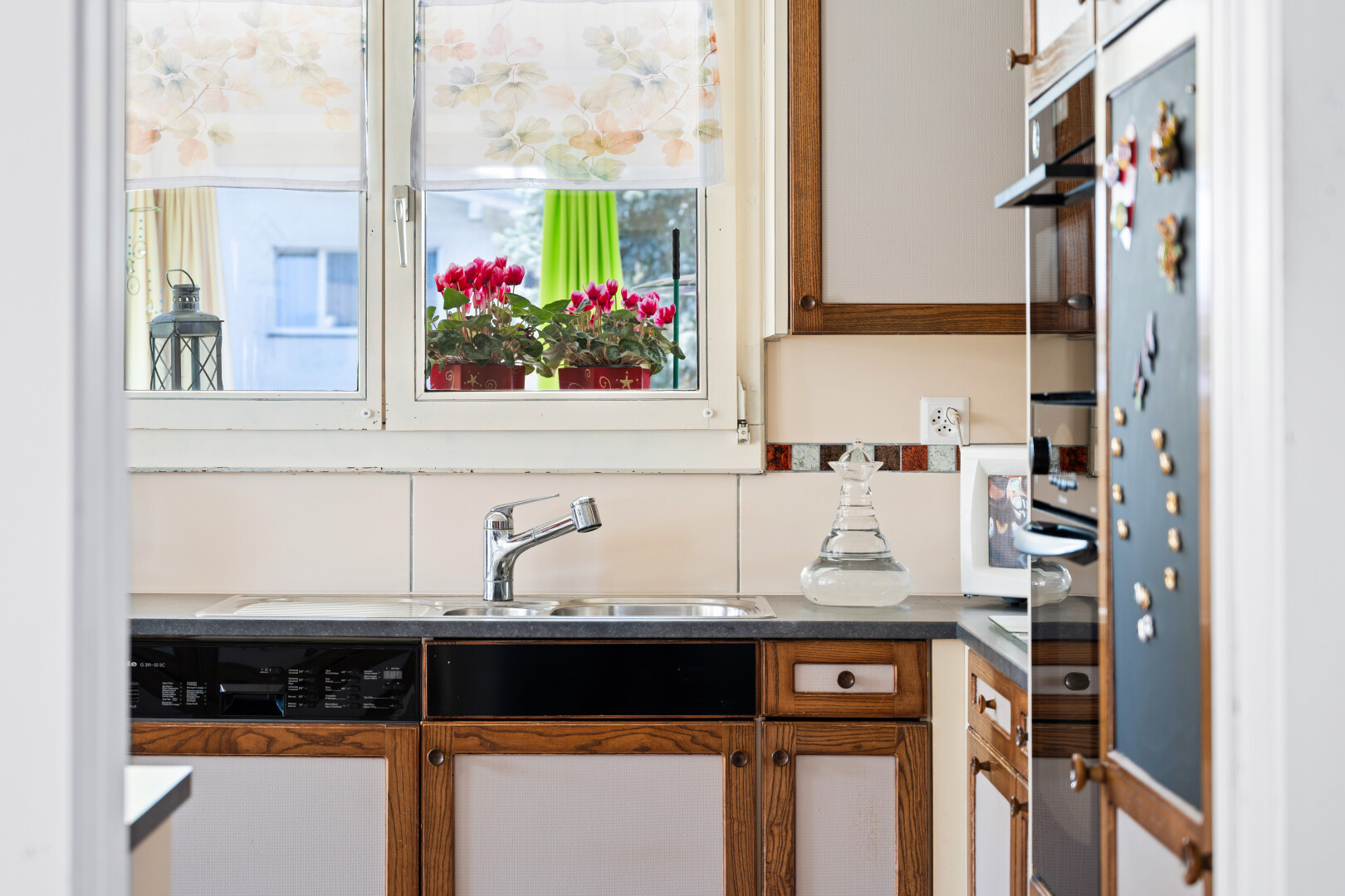 kitchen featuring wood finish cabinetry, dishwasher, light countertops, and refrigerator