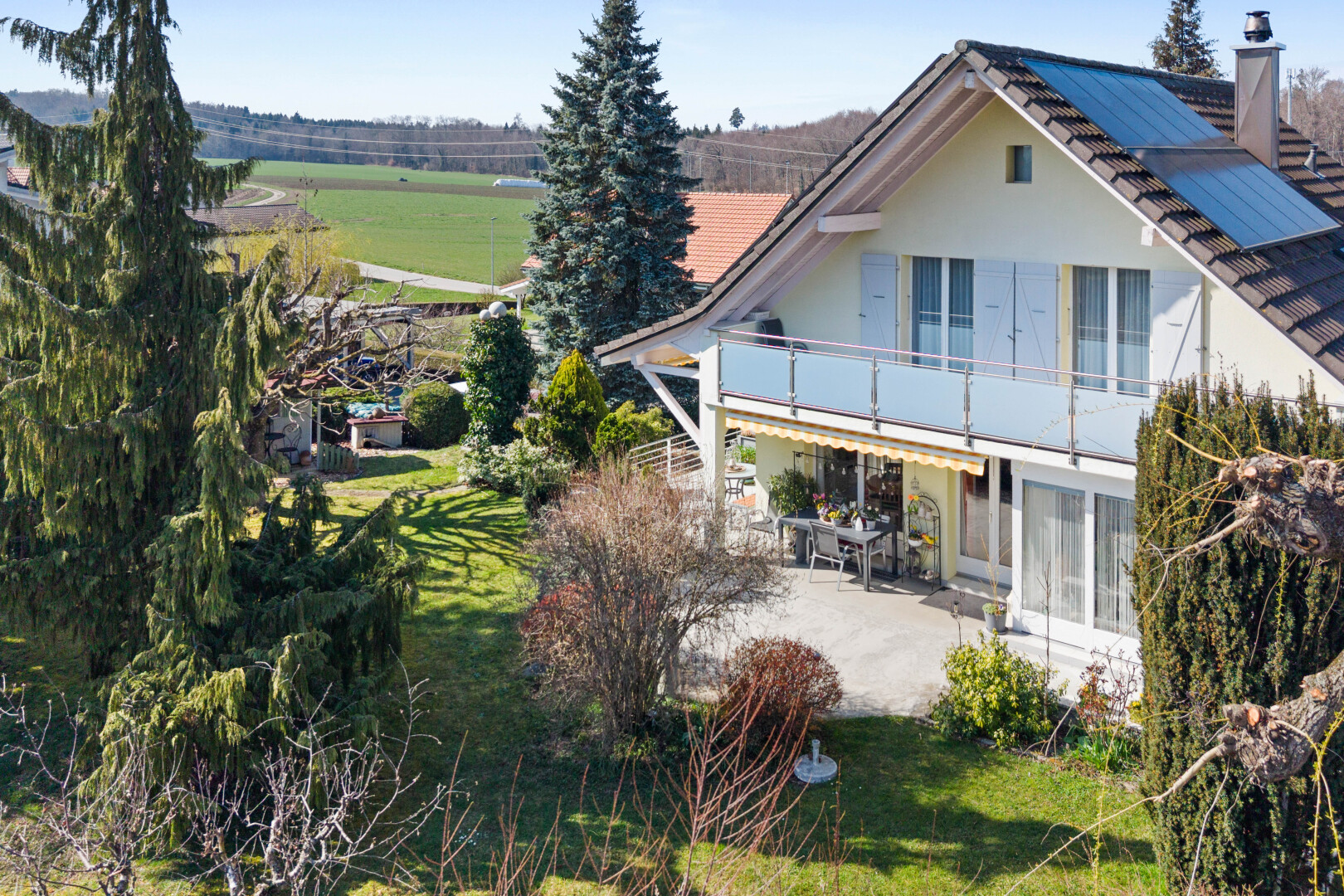 view of home featuring a balcony, a patio area, a yard, and a chimney