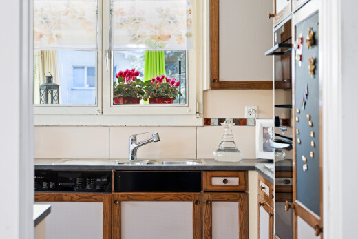 kitchen featuring wood finish cabinetry, dishwasher, light countertops, and refrigerator
