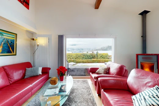 salon avec poutres apparentes, lumière naturelle, haut plafond, et plancher de bois