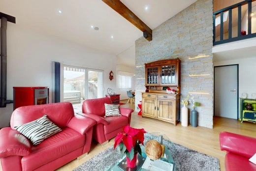 salon avec plafond voûté, poutres apparentes, haut plafond, lumière naturelle, et plancher de bois
