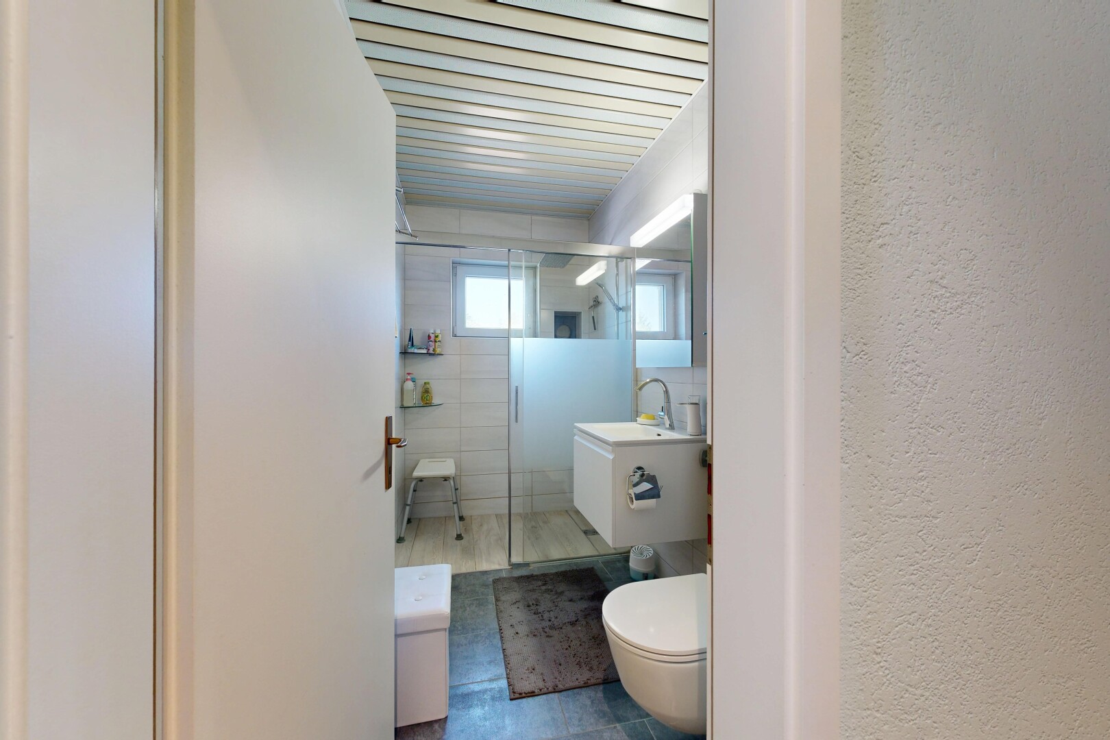 salle de bains avec douche, salle de bain complète, toilette, miroir, et lavabo (ou coiffeuse selon le contexte)