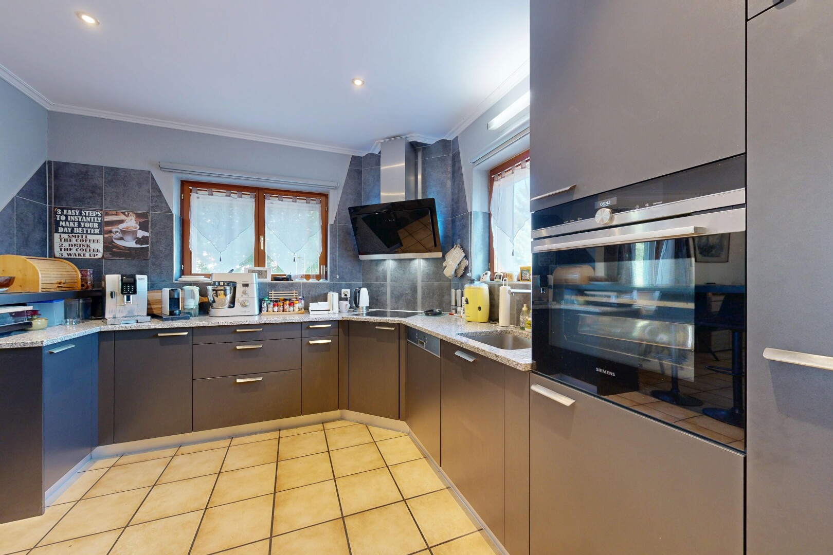 cuisine avec light countertops, hotte, four, light floor, et éclairage encastré