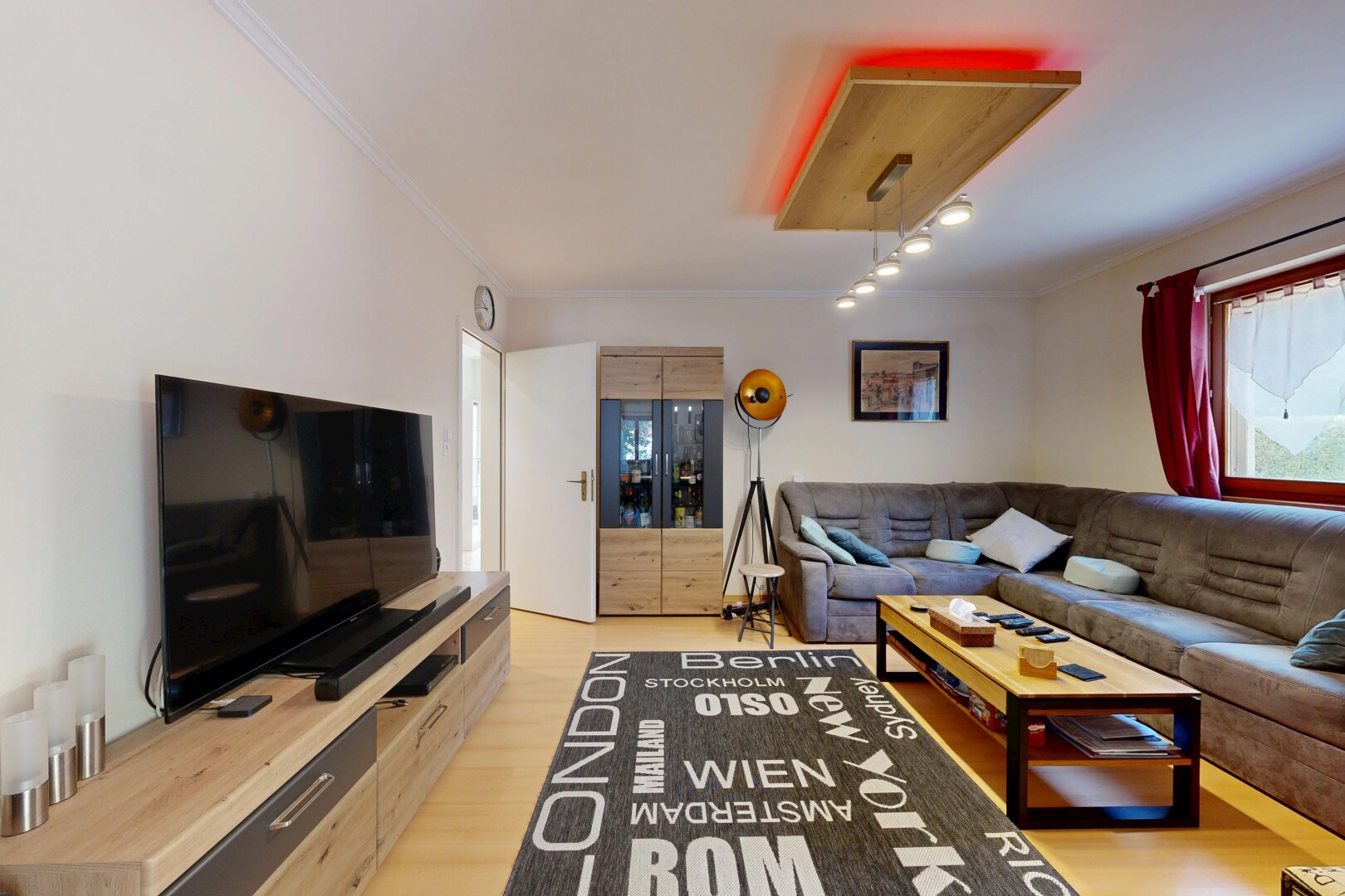 salon avec télévision, drywall, cloison sèche, wood finish floor, et sol en finition bois