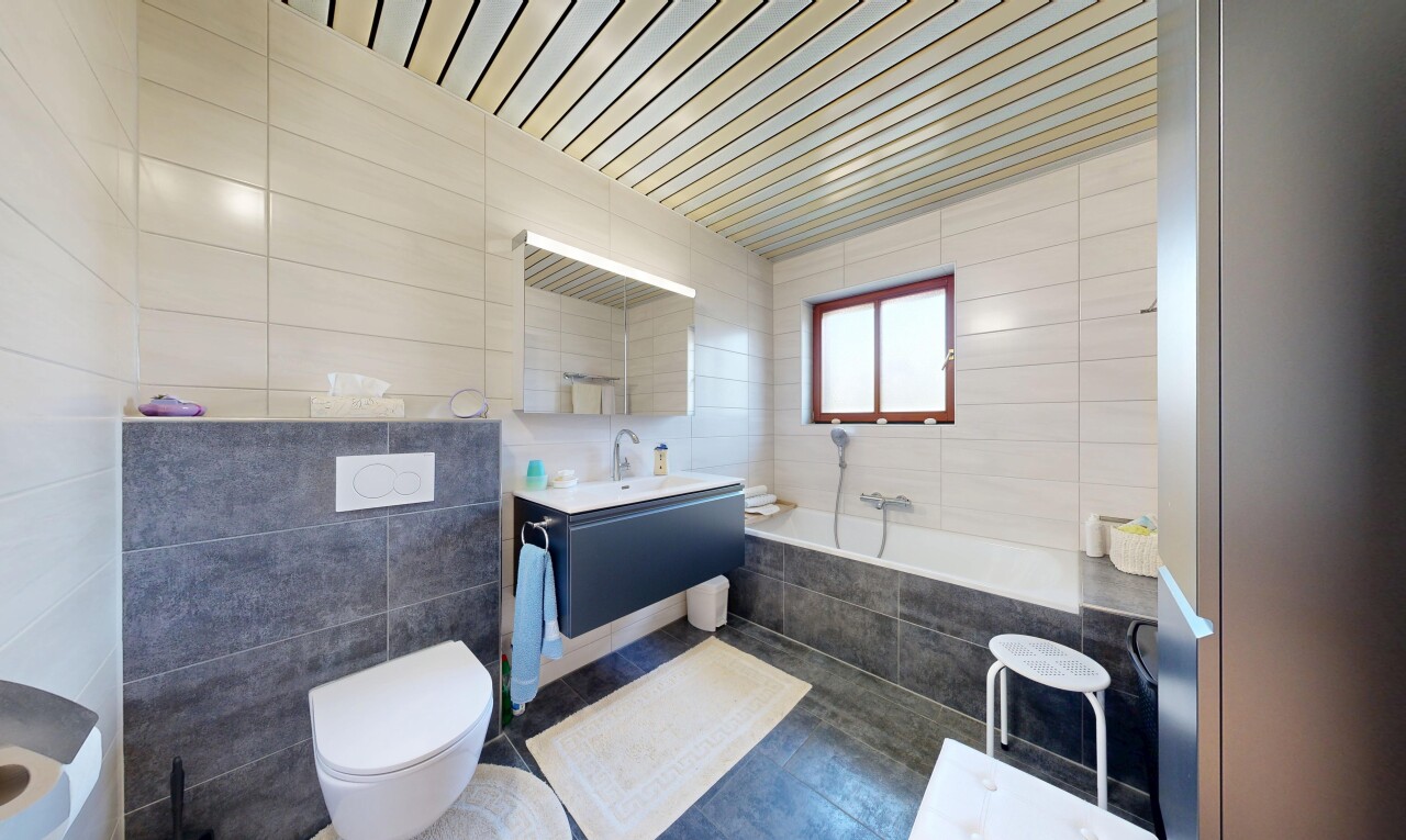salle de bains avec mur en carrelage, tile wall, bain, miroir, et lavabo (ou coiffeuse selon le contexte)