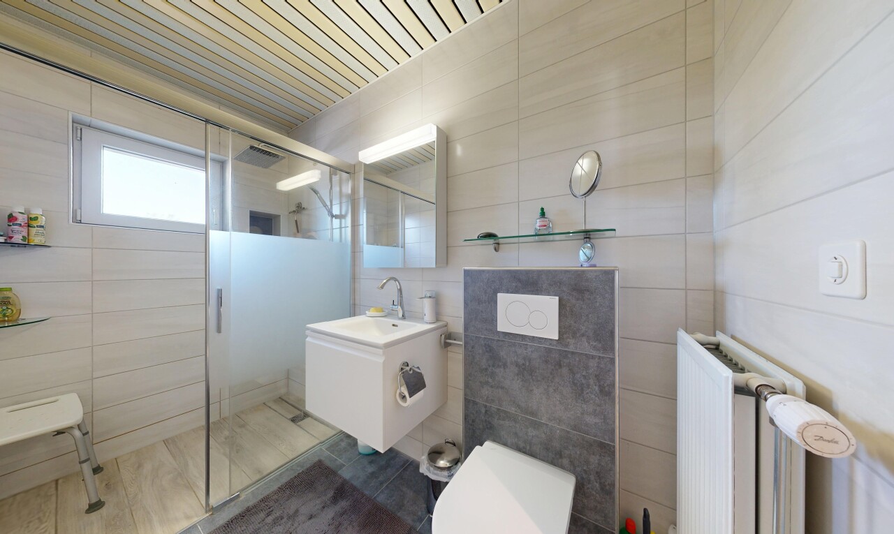salle de bains avec douche, salle de bain complète, miroir, radiateur, et lavabo (ou coiffeuse selon le contexte)
