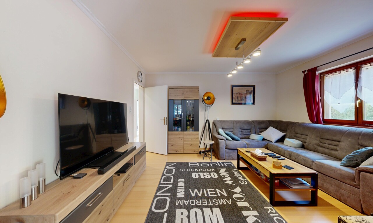 salon avec télévision, drywall, cloison sèche, wood finish floor, et sol en finition bois