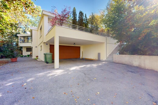 view of property with driveway, stucco siding, and a balcony