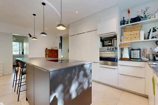 küche mit flat panel cabinets, schränke mit flachen paneelen, dark countertops, arbeitsplatten, und pendelleuchte
