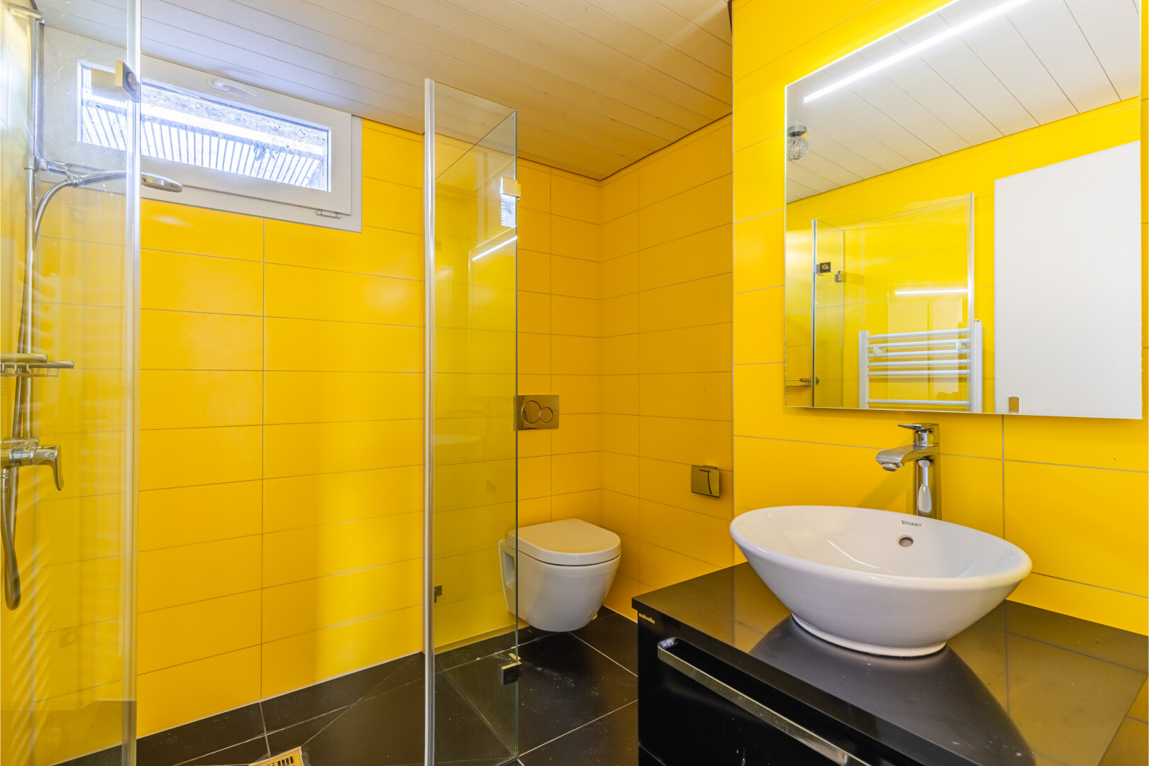 salle de bains avec chauffe-serviettes, miroir, salle de bain complète, lavabo (ou coiffeuse selon le contexte), et douche