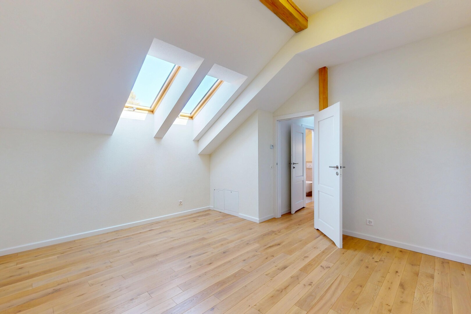 pièce vide avec pièce supplémentaire, sol en finition bois, plafond voûté, cloison sèche, et puits de lumière