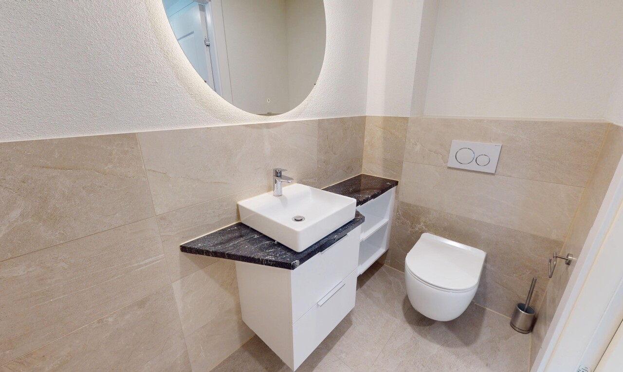 salle de bains avec miroir, évier, lavabo (ou coiffeuse selon le contexte), et toilette