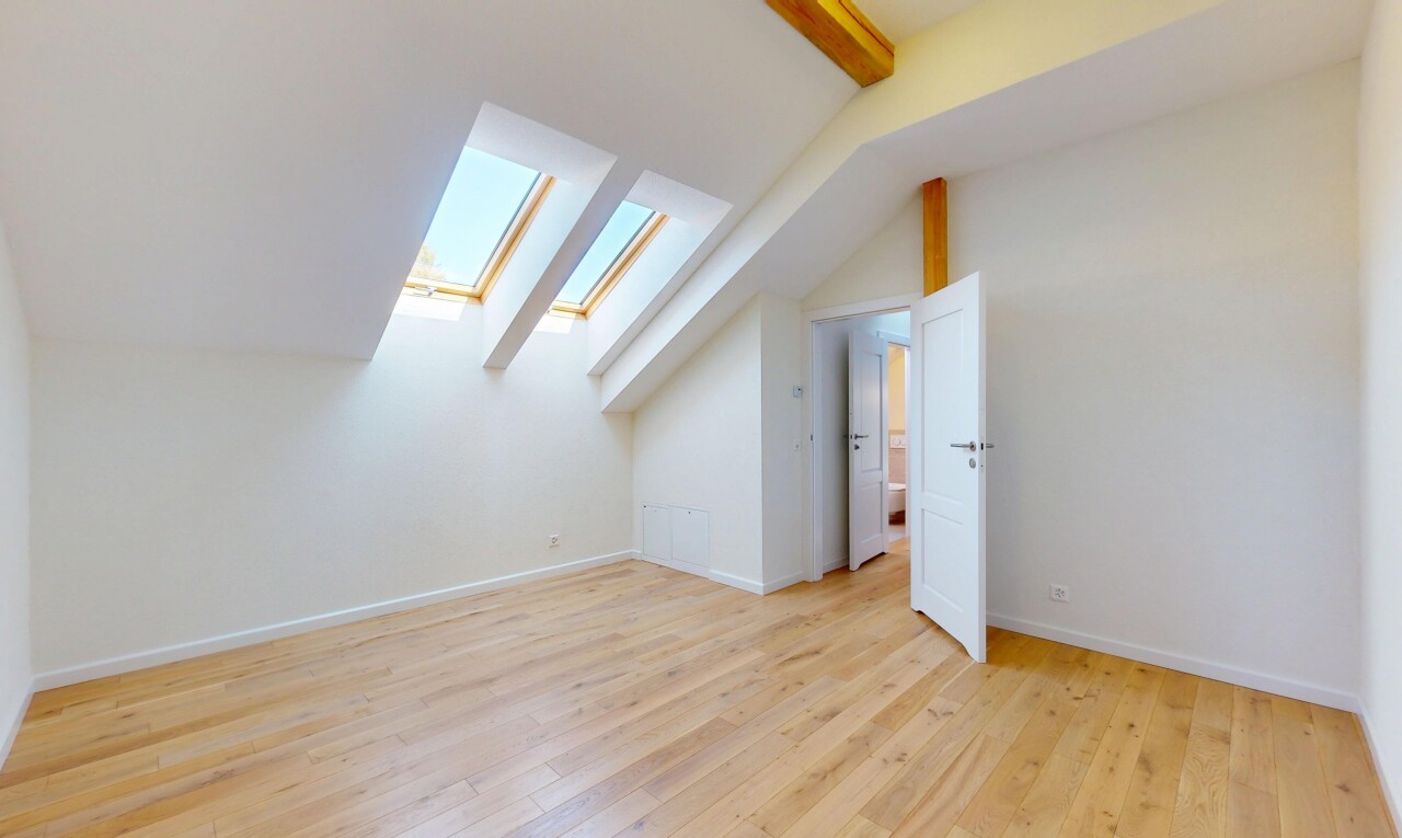 pièce vide avec pièce supplémentaire, sol en finition bois, plafond voûté, cloison sèche, et puits de lumière
