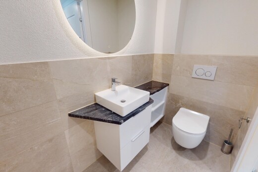 salle de bains avec miroir, évier, lavabo (ou coiffeuse selon le contexte), et toilette