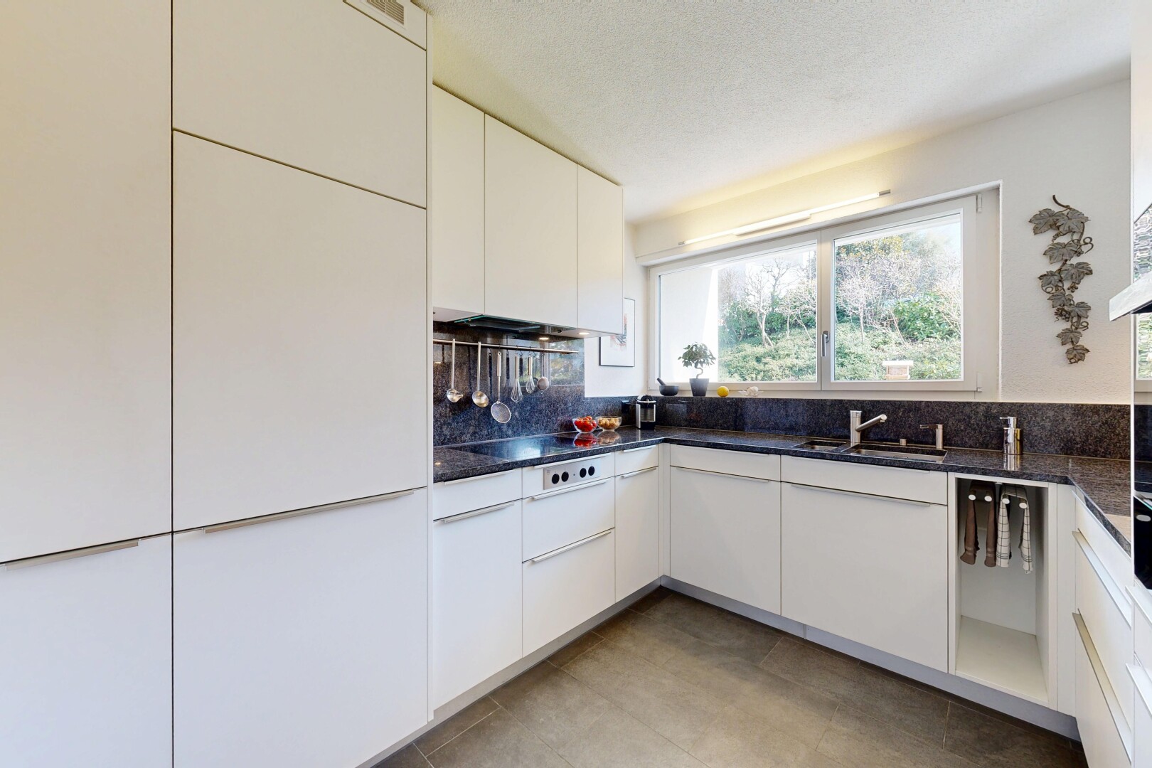 cuisine avec dark countertops, armoires blanches, white cabinets, lumière naturelle, et natural light
