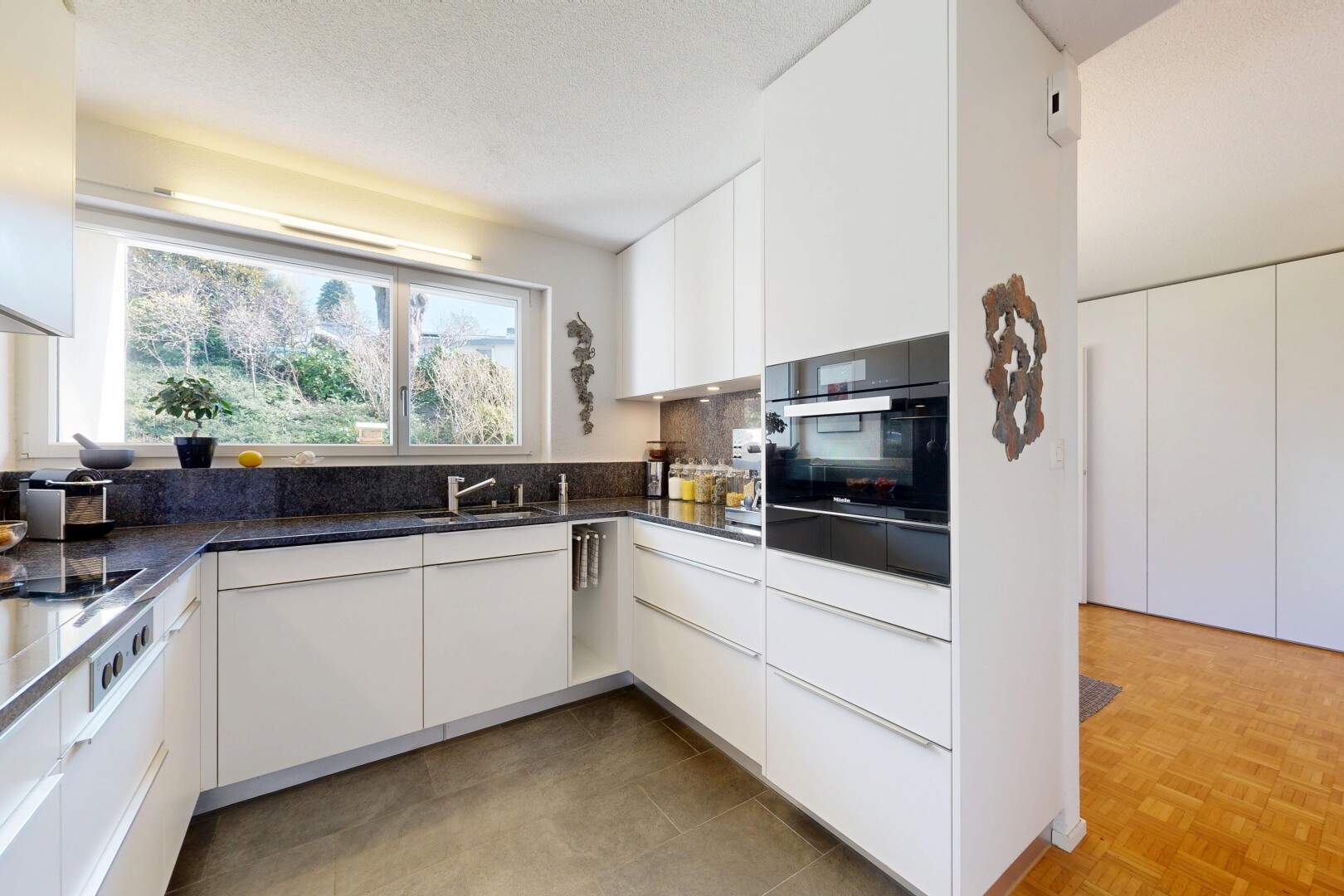 cuisine avec armoires blanches, white cabinets, dark countertops, four, et lumière naturelle