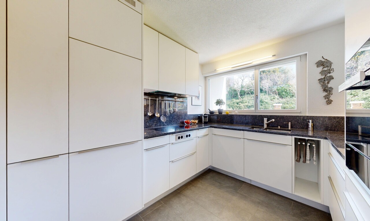 cuisine avec dark countertops, armoires blanches, white cabinets, lumière naturelle, et natural light