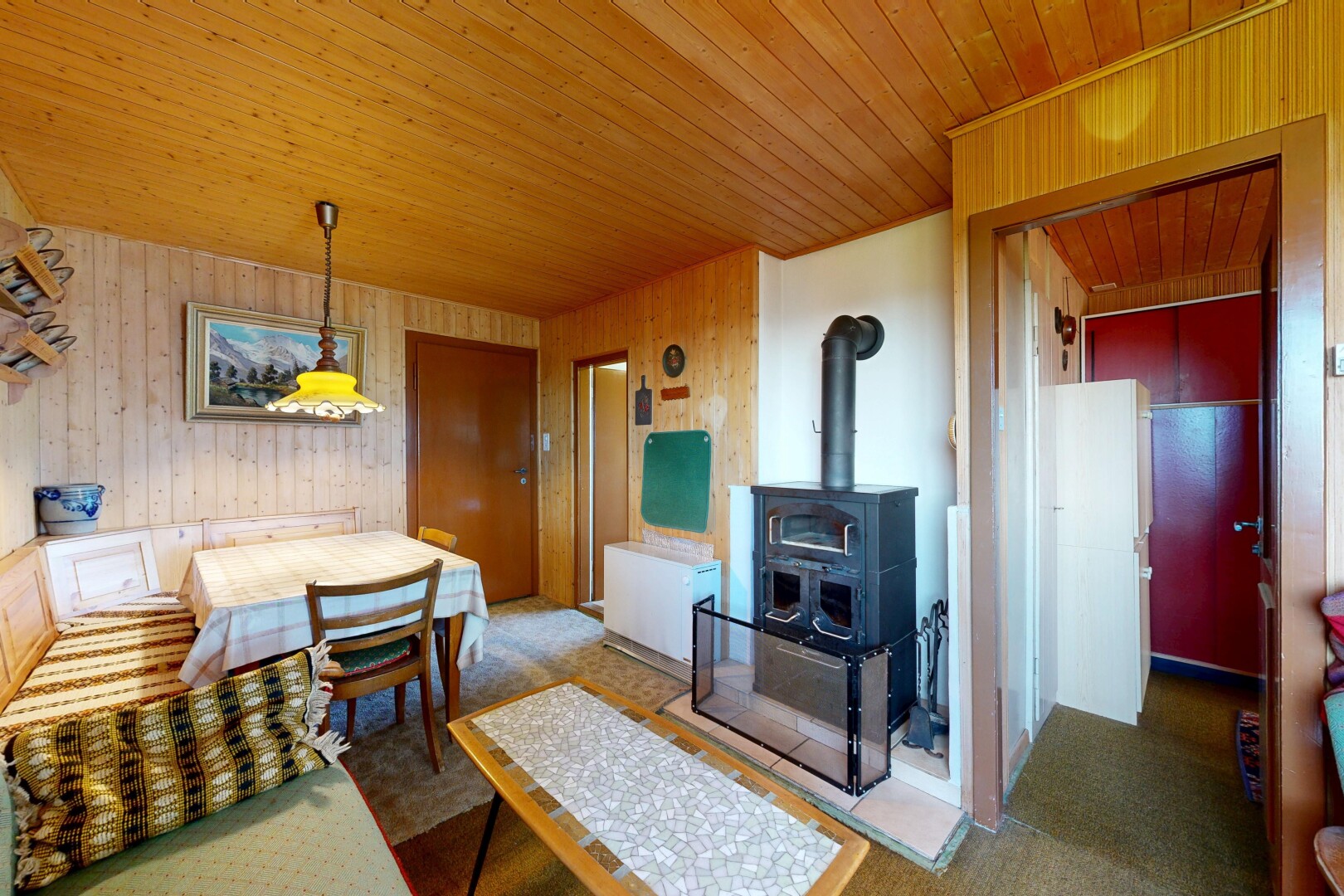 wohn- / esszimmer mit teppich, carpet, holzofen, inside property, und holzwand
