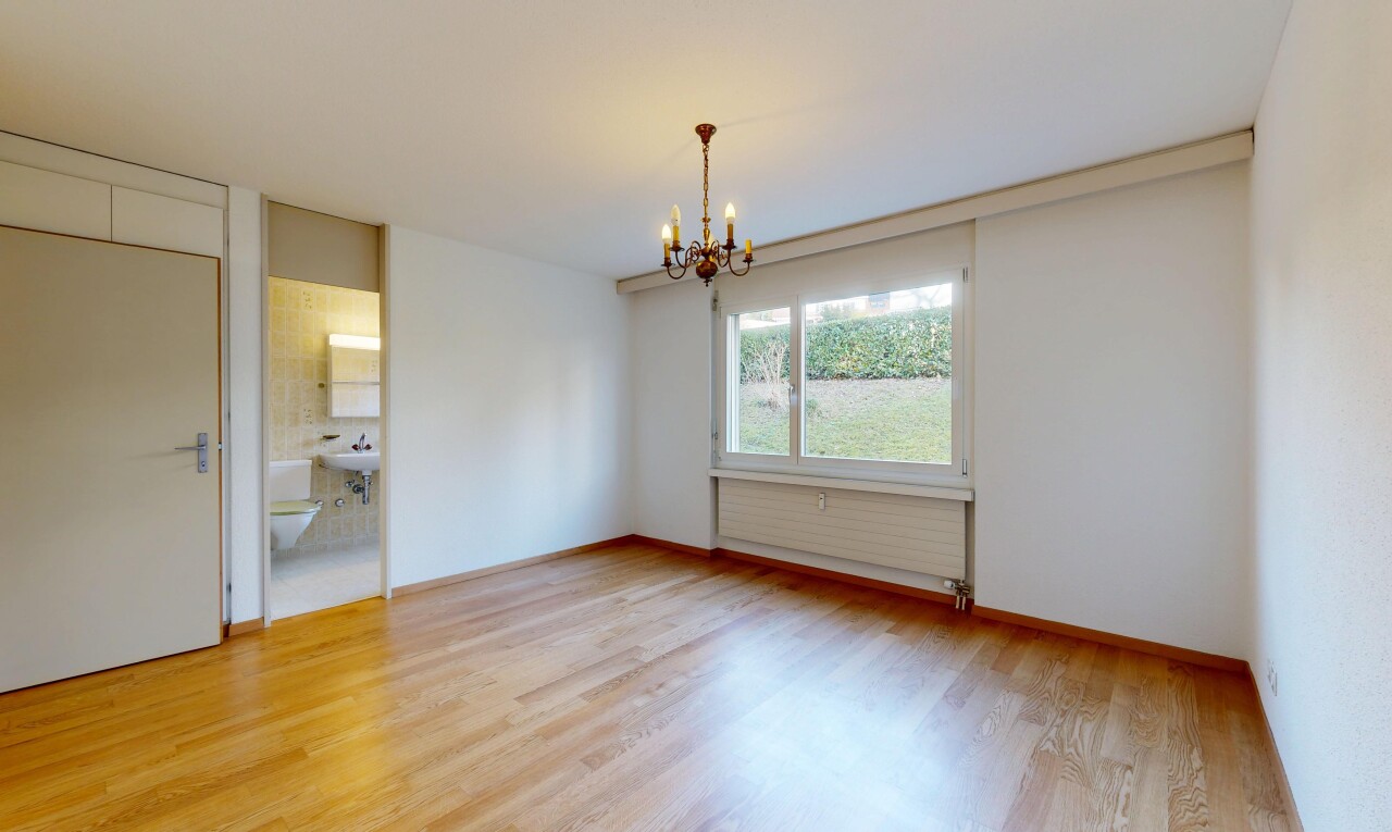 pièce vide avec inside property, sol en finition bois, wood finish floor, lustre remarquable, et lumière naturelle
