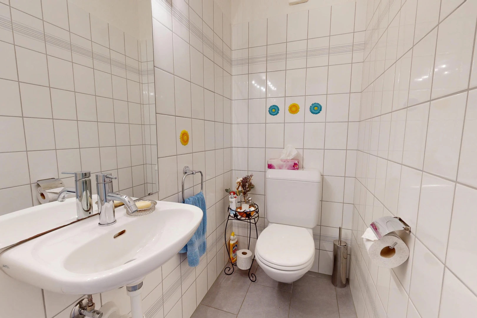 salle de bains avec toilette, évier, mur en carrelage, tile wall, et miroir