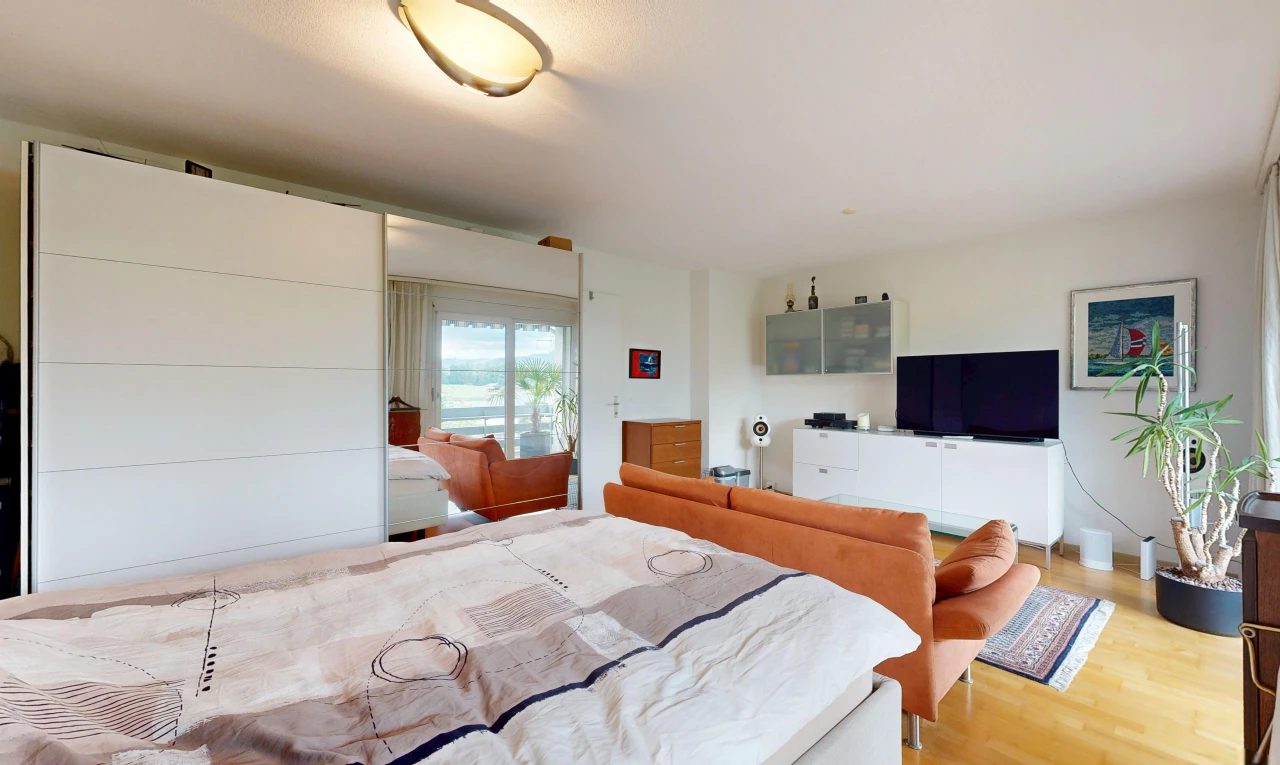 chambre avec télévision, drywall, cloison sèche, wood finish floor, et sol en finition bois