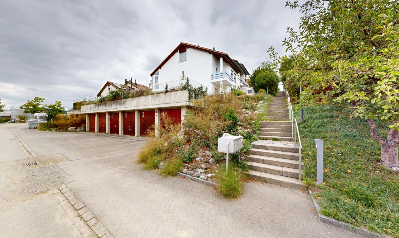 façade avec garages communautaires, escaliers, overcast, et property visible