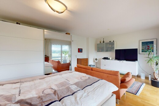 chambre avec télévision, drywall, cloison sèche, wood finish floor, et sol en finition bois