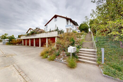 façade avec garages communautaires, escaliers, overcast, et property visible