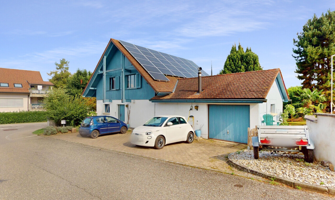 façade avec property visible, panneaux solaires, bardage vertical, day time, et aire de stationnement
