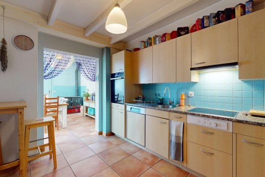 kitchen with backsplash, decorative light fixtures, beam ceiling, light tile patterned floors, and dark stone counters