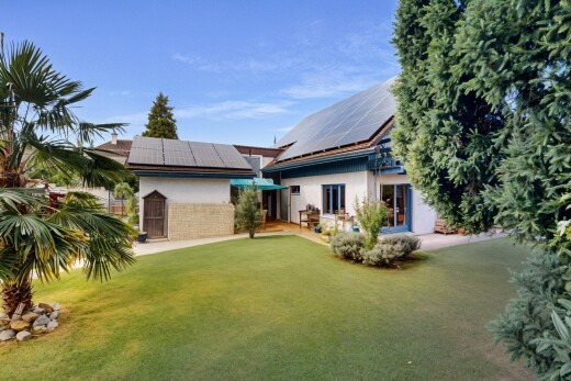 outdoor house with a lawn, stucco siding, solar panels, and brick siding
