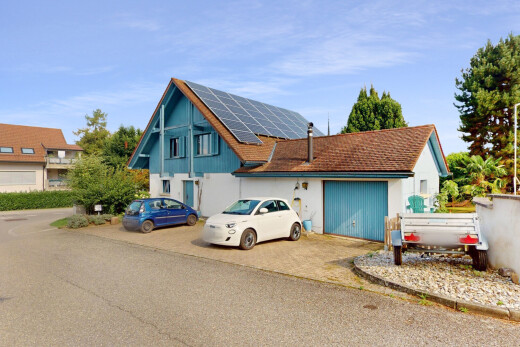 façade avec property visible, panneaux solaires, bardage vertical, day time, et aire de stationnement