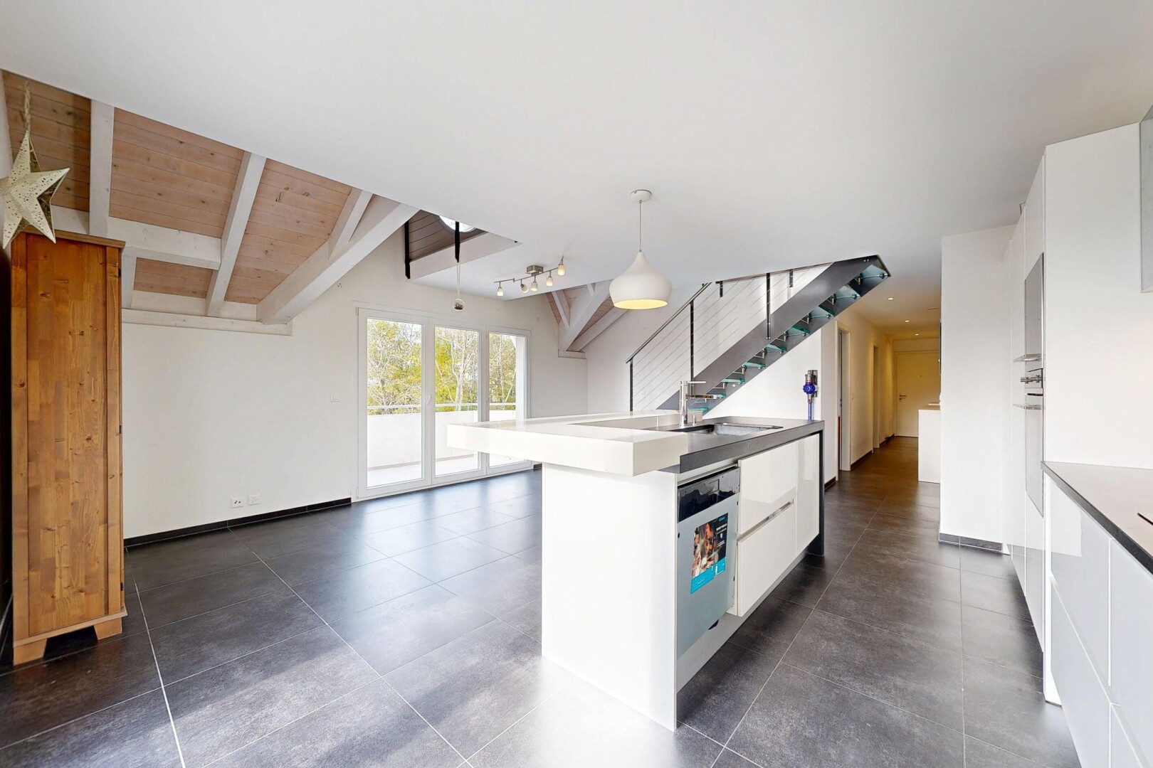kitchen with white cabinetry, a center island with sink, pendant lighting, dishwasher, and beamed ceiling