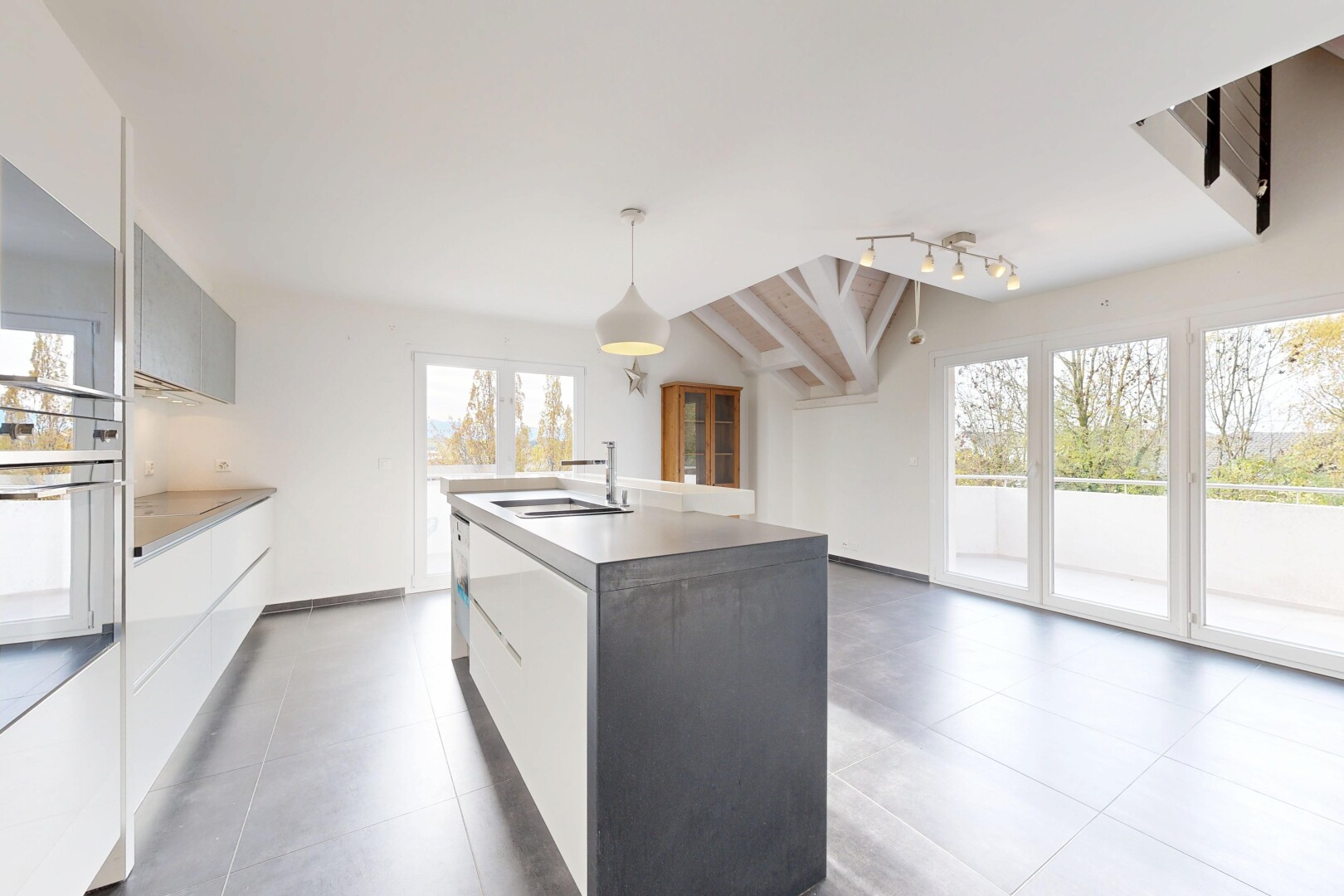 kitchen featuring modern cabinets, pendant lighting, an island with sink, lofted ceiling, and white cabinets