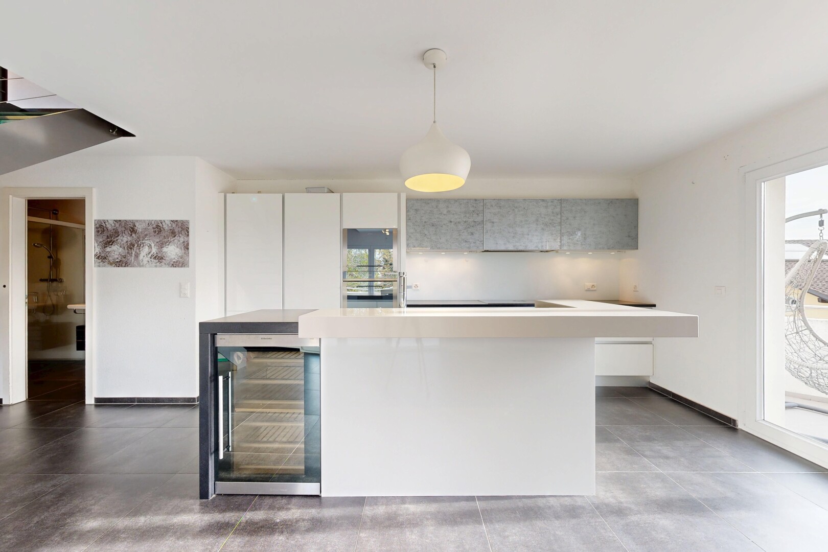 kitchen with wine cooler, hanging light fixtures, modern cabinets, light countertops, and a kitchen island