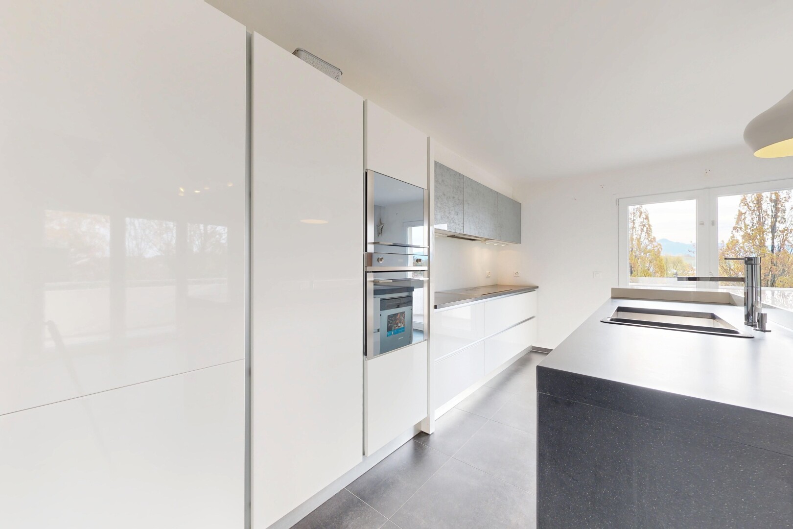 kitchen featuring modern cabinets, stainless steel oven, light countertops, and concrete flooring