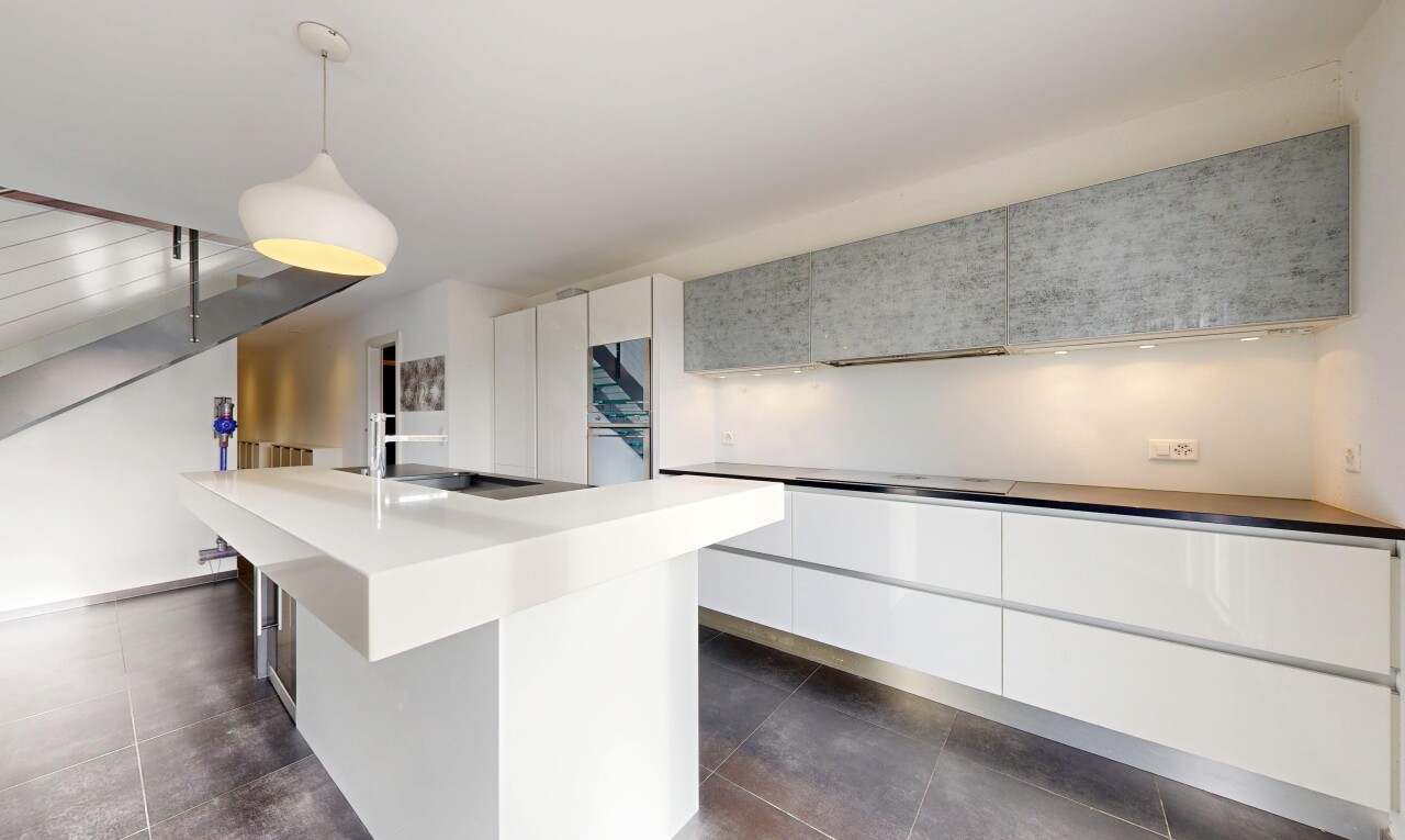 kitchen featuring decorative light fixtures, white cabinetry, modern cabinets, an island with sink, and light countertops
