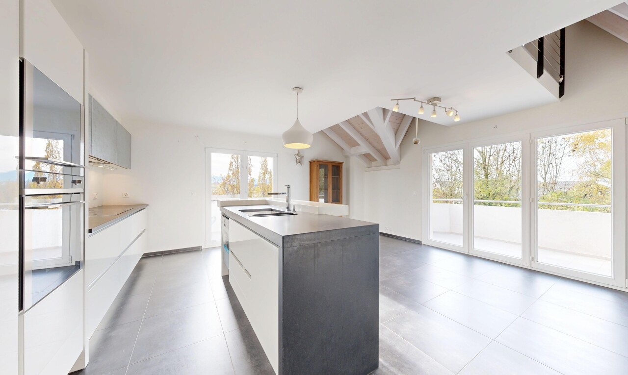 kitchen featuring modern cabinets, pendant lighting, an island with sink, lofted ceiling, and white cabinets