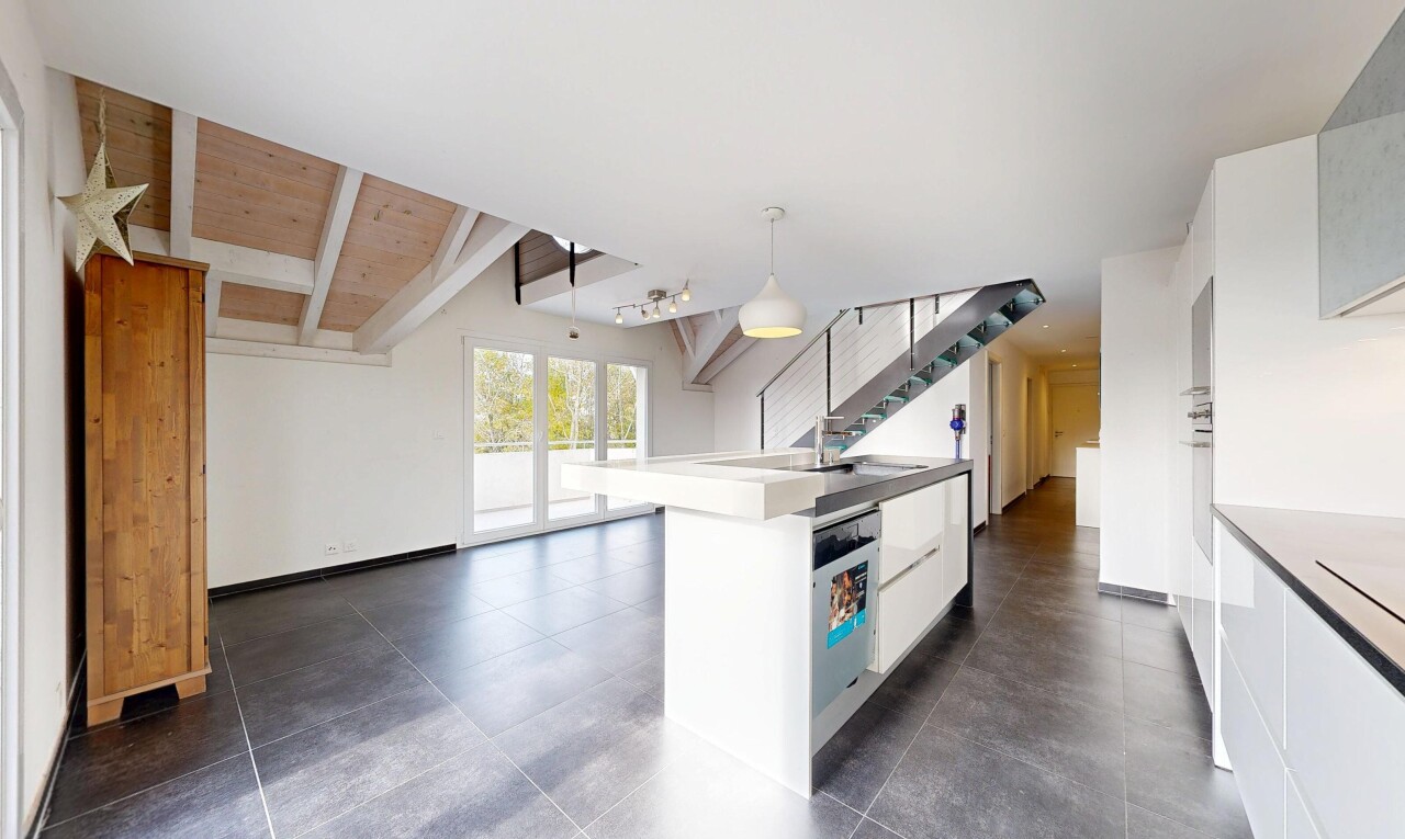 kitchen with white cabinetry, a center island with sink, pendant lighting, dishwasher, and beamed ceiling