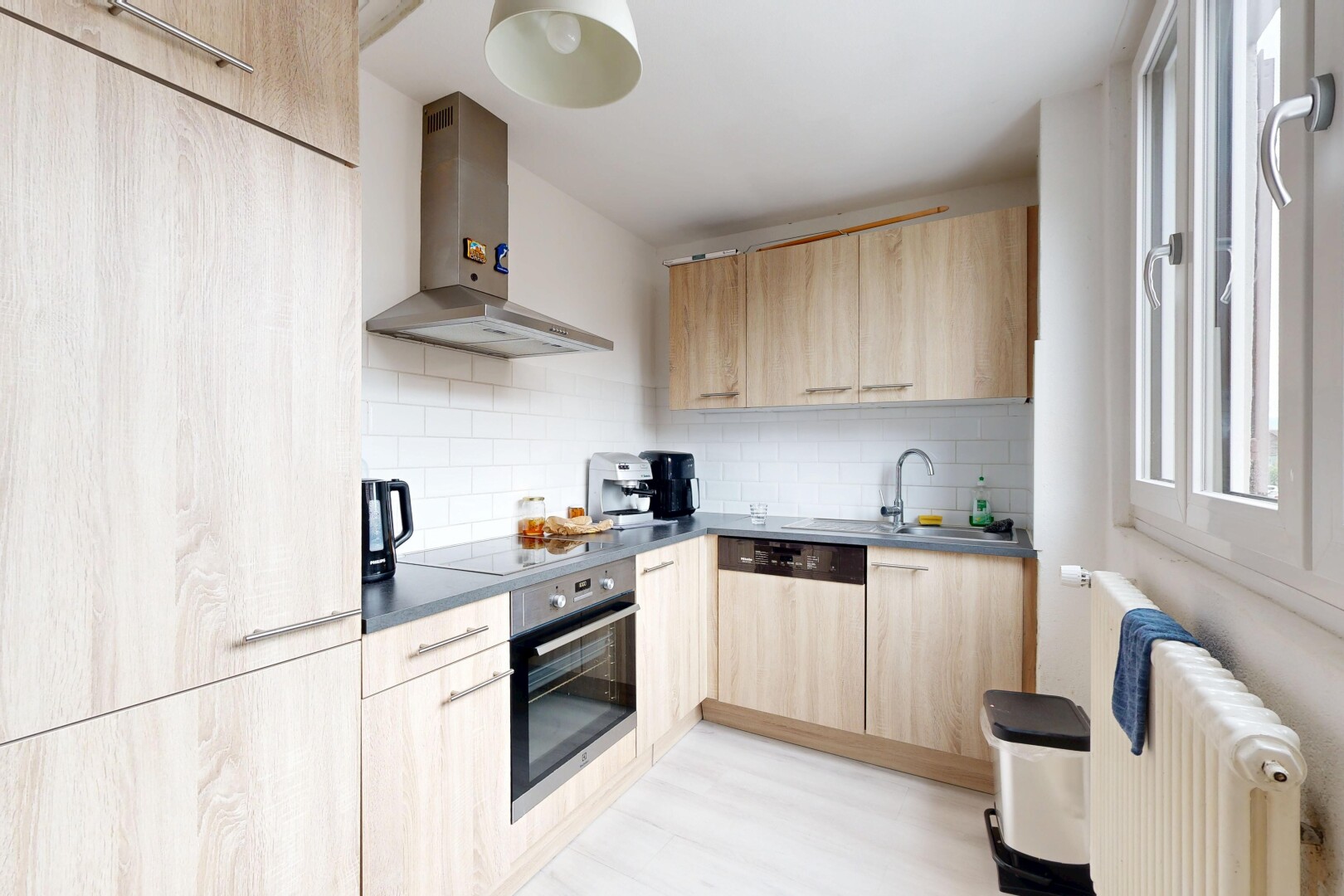 cuisine avec hotte, radiateur, light brown cabinets, armoires marron clair, et backsplash