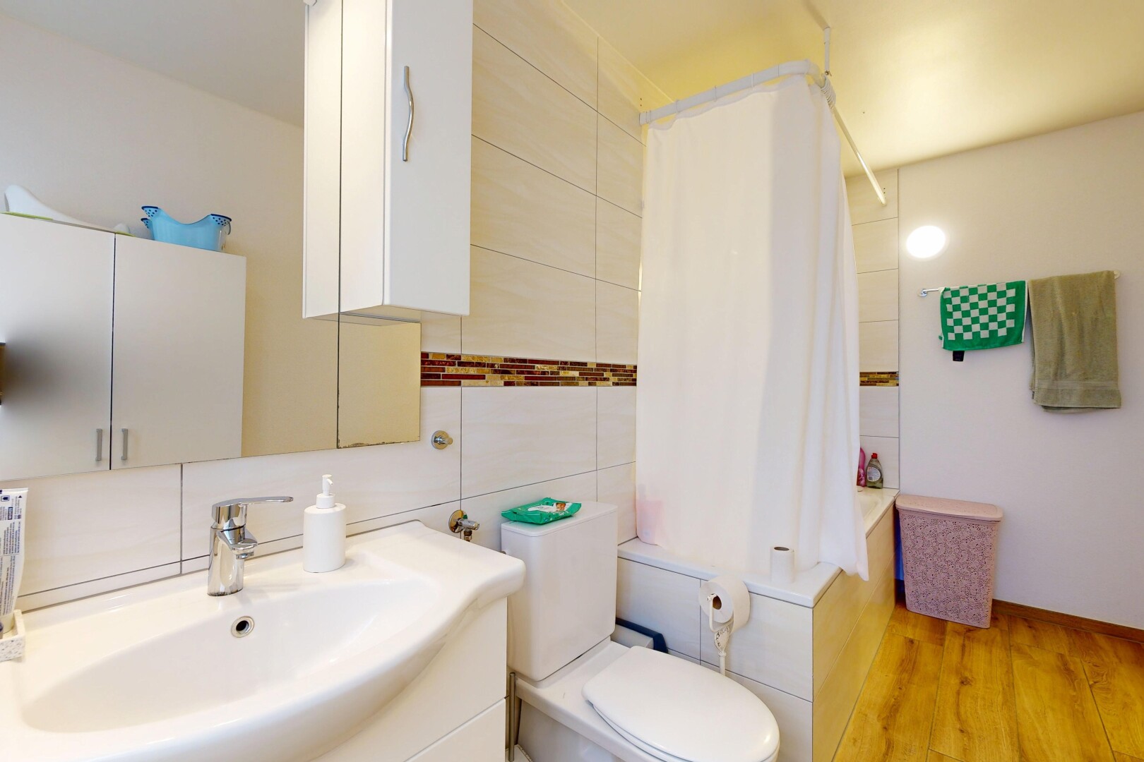 salle de bains avec salle de bain complète, lavabo (ou coiffeuse selon le contexte), miroir, toilette, et évier