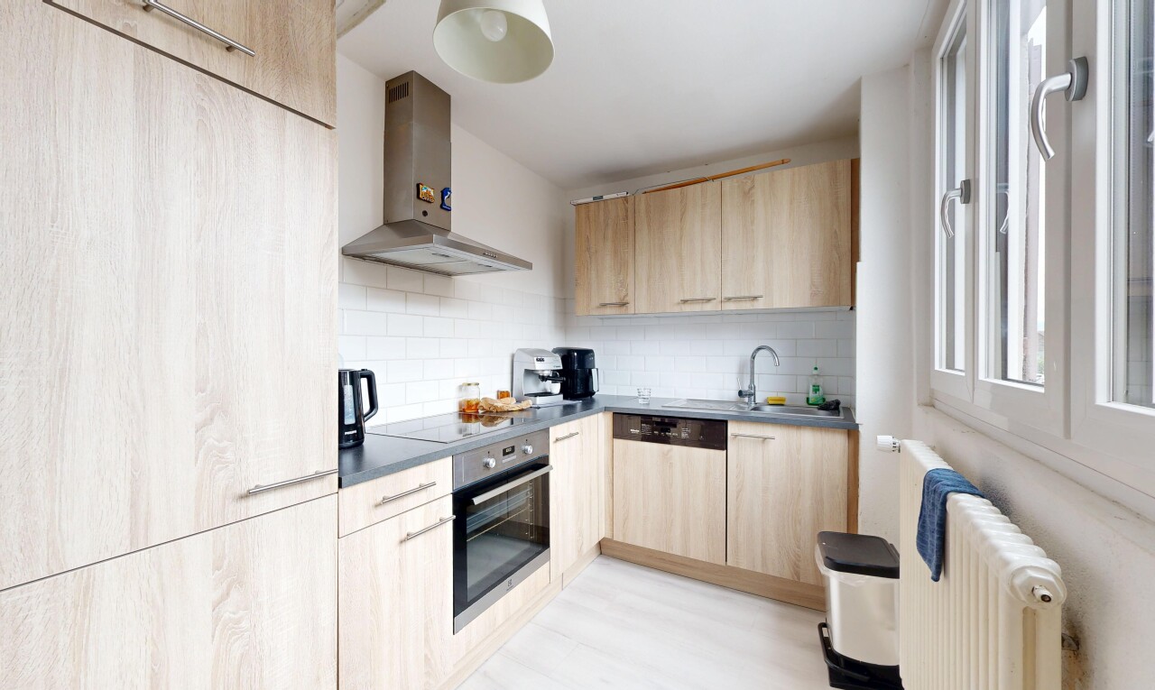 cuisine avec hotte, radiateur, light brown cabinets, armoires marron clair, et backsplash