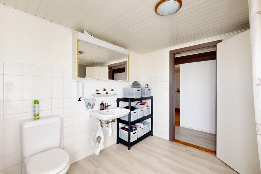 salle de bains avec mur en carrelage, tile wall, miroir, toilette, et sol en finition bois