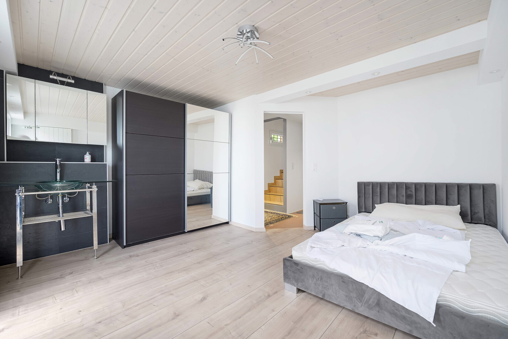 room / bedroom featuring light wood-style floors, a wood ceiling with exposed beams, and connected bathroom