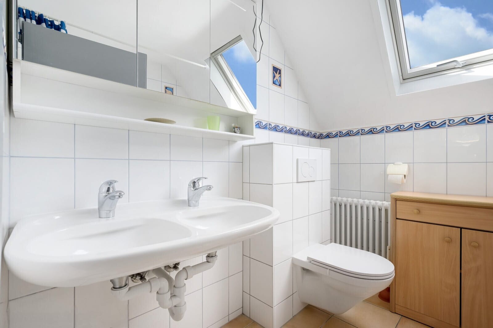 bathroom with radiator heating unit, tile walls, vaulted ceiling, a skylight, and light tile patterned floors
