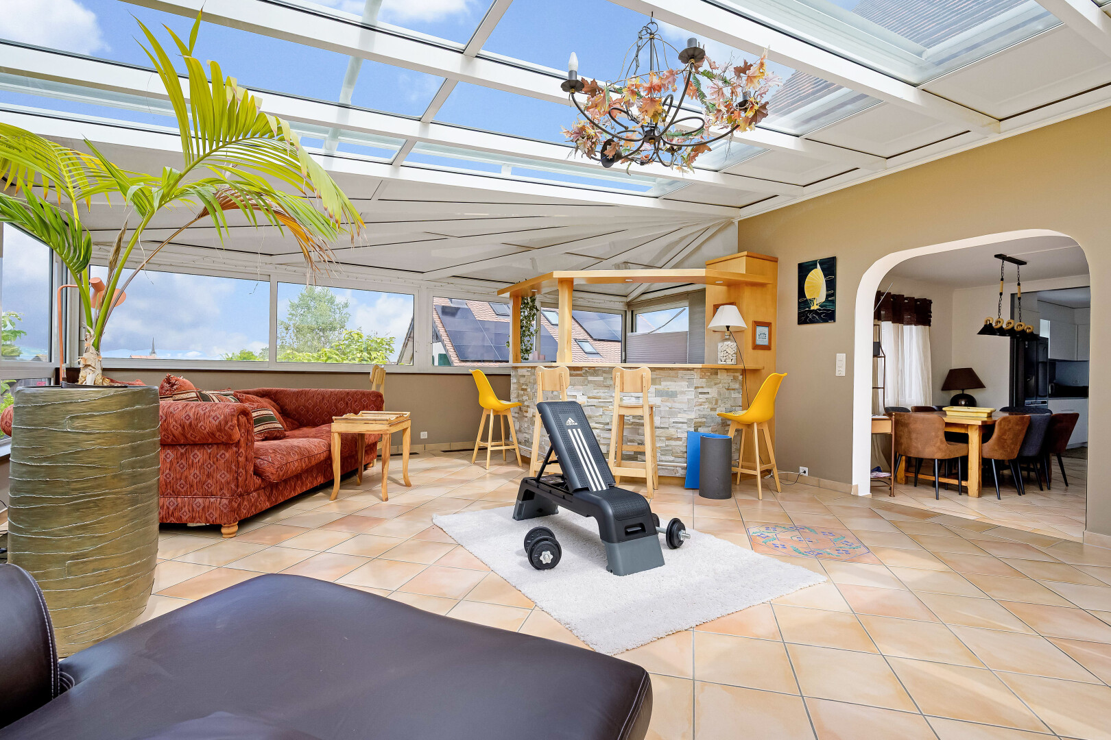 gym with a chandelier, tile patterned flooring, arched walkways, and plenty of natural light