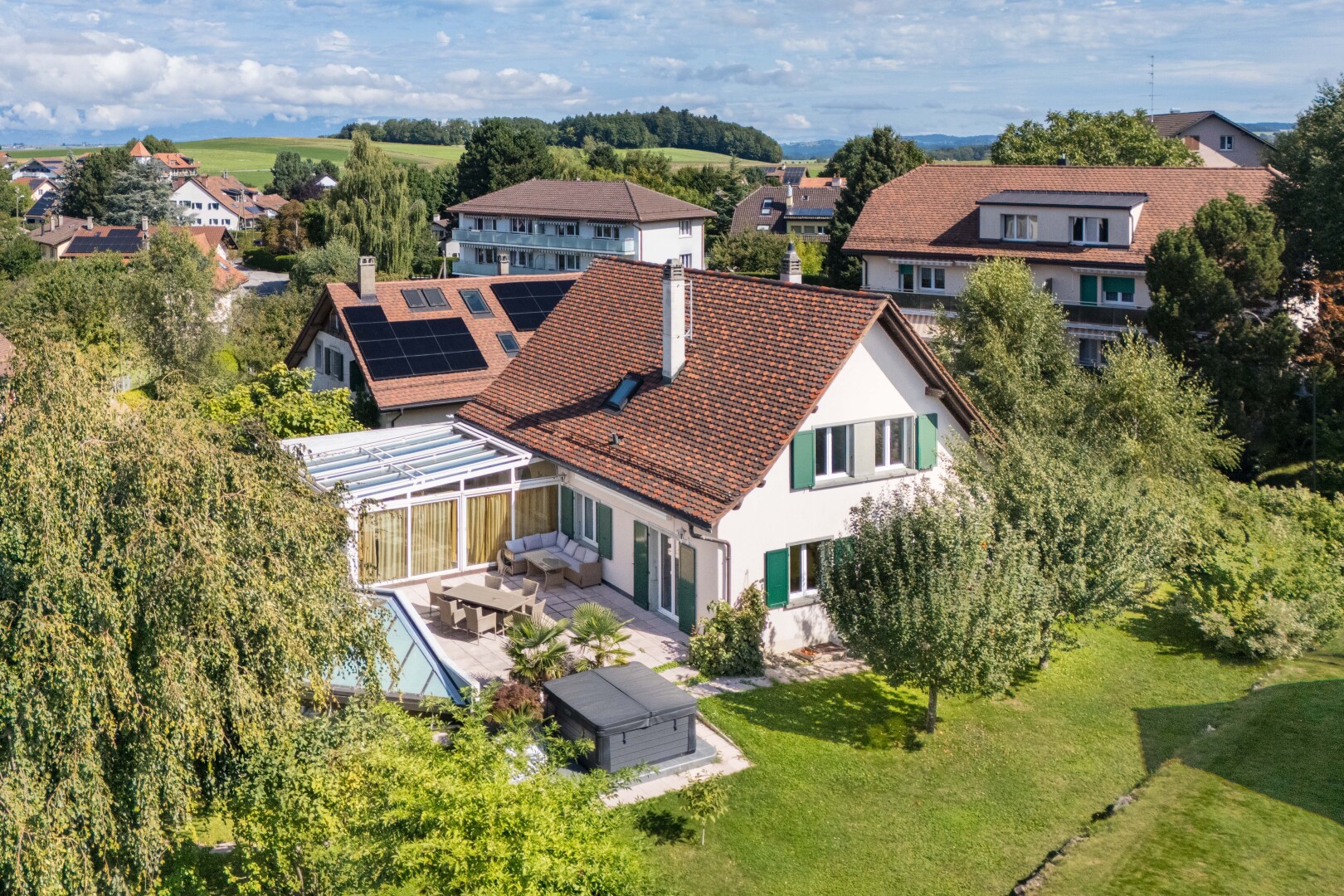 view of home featuring roof mounted solar panels, a patio, a yard, a residential view, and a chimney
